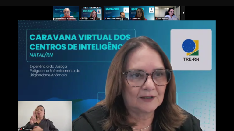 Print de uma sala de reuniões virtual. No topo aparecem janelas abertas com participantes, e no ...